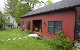 Image of two residential structures, featuring a red building and a larger light-colored house, illustrating the concept of accessory dwelling units (adus).