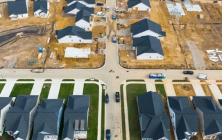 An aerial view of a residential neighborhood showcasing completed and under-construction homes, representing an expanding housing development.