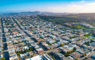 Aerial view of a u. S. Metropolis showcasing a dense grid-like urban environment with residential and commercial buildings, streets, and parks.