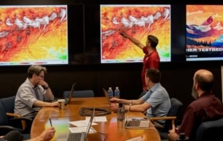 Engaged team analyzing wildfire risk using ai and weather maps in a conference setting