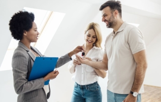 A real estate agent handing over keys to happy clients in a modern setting