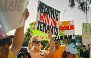 Image of protesters holding signs at a rent control rally