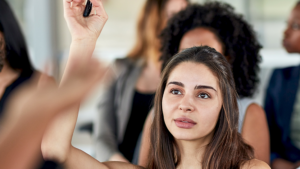 A woman raising her hand during an in-person real estate class.