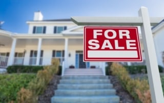 For sale sign in front of a two-story house