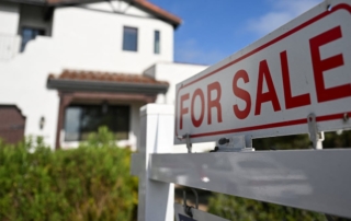 Close-up of a for sale sign with house in the background