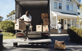 Moving scene with a man unloading boxes from a truck in front of a house