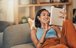 Person lounging on a sofa engaging with a tablet