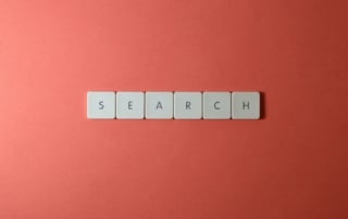 Image of six white tiles spelling "search" on a reddish-orange background