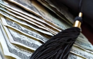 Close-up of us dollar bills with a graduation cap