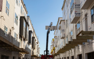 Image of a construction site featuring multi-story residential buildings in progress under clear blue skies.