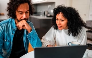 Two people collaborating over a laptop in a modern kitchen setting