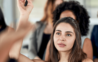 Young woman raising hand in a classroom setting