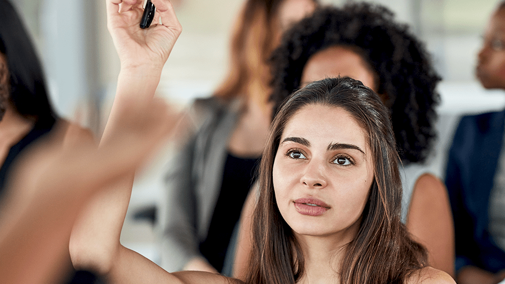 Young woman raising hand in a classroom setting