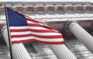 Low-angle view of neoclassical architecture with a waving american flag