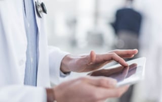 A healthcare professional using a tablet in a clinical setting, representing ai integration in patient diagnostics.