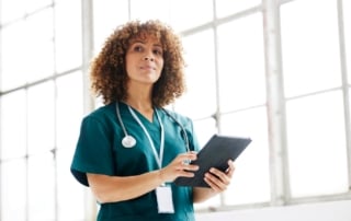 A healthcare professional in green scrubs interacting with a tablet, symbolizing digital transformation in healthcare.