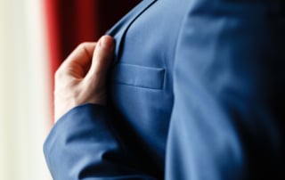 Image of a person in a blue suit adjusting the lapel, symbolizing professionalism in real estate