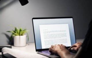 Hands typing on a laptop amidst a minimalist home office setting, representing remote work and its impact on real estate investment in india.