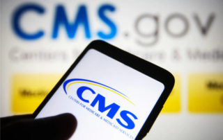 Close-up of a smartphone displaying the cms logo, surrounded by a blurred background showing the cms. Gov website