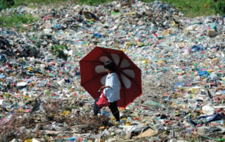 A person walking through a polluted area with garbage and plastic waste