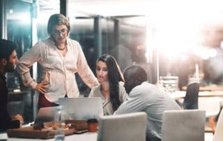 Group of four people discussing business around a laptop in an office setting