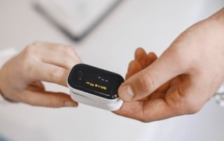 Close-up of a person using a fingertip pulse oximeter to measure oxygen saturation levels