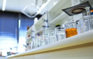 Image of a laboratory countertop with glass beakers, including one with an orange substance, highlighting a research environment potentially linked to sclc biomarkers.