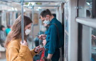 Image showing passengers in a public transit vehicle, all wearing face masks, depicting a scene related to modern health concerns.