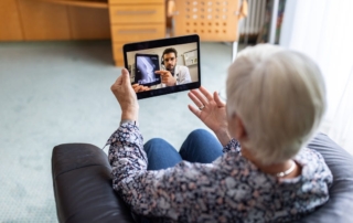 Image of an older woman participating in a telemedicine session from her home.