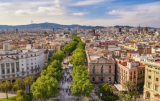 A bustling city street lined with trees, showcasing a mix of historic and modern architecture.