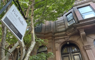 Classic townhouse with stone facade and real estate sign