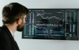 A man studying a large screen filled with financial charts, graphs, and tables related to stock market trends and cryptocurrency trading, representing ai-driven investment analysis tools.