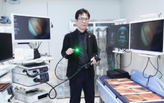 A person in a medical facility holding an endoscope with a green light, surrounded by monitors displaying ai-enhanced medical images