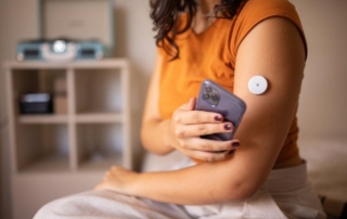 A person uses a smartphone with a wearable health device on their arm