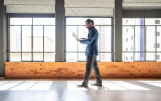 Person walking indoors with a laptop in a modern office environment