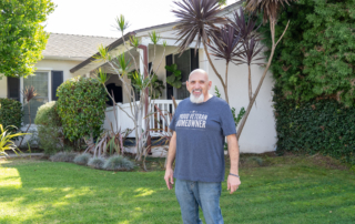 A proud veteran standing in front of his new home