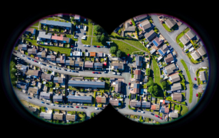 Aerial view of a suburban neighborhood seen through binoculars, illustrating a housing market perspective