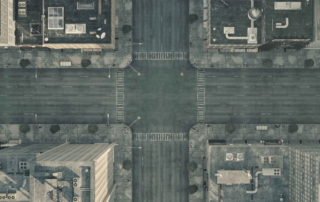 Aerial view of a quiet city intersection with empty streets and flat-roofed buildings