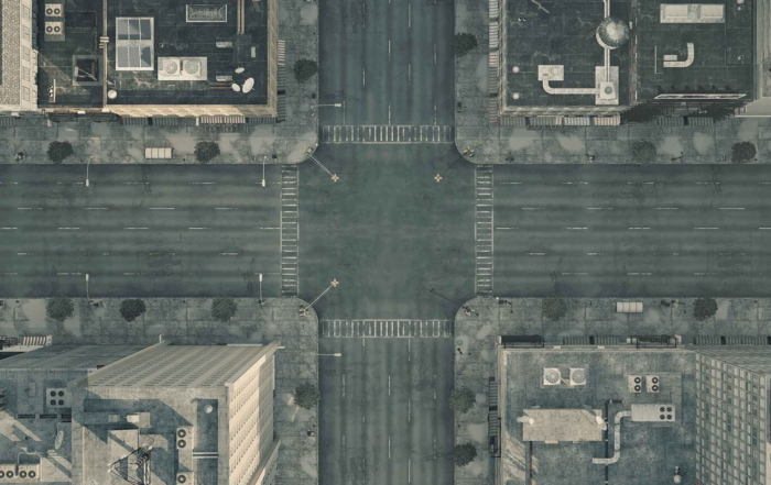 Aerial view of a quiet city intersection with empty streets and flat-roofed buildings