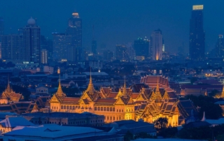 A night view of bangkok, featuring the illuminated grand palace architecture against a modern skyline.