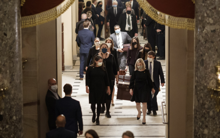 Group of people walking through an ornate hallway in a government building