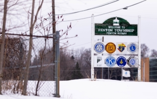 A welcome sign in fenton township from the fenton rotary amidst a snowy backdrop