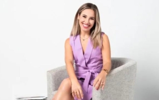 Person seated in a modern gray chair, smiling in a light purple wrap dress