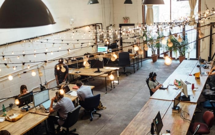 A modern open-plan office with desks, computers, and people working.