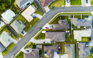 Aerial view of a suburban neighborhood with single-family homes, driveways, and solar panels.