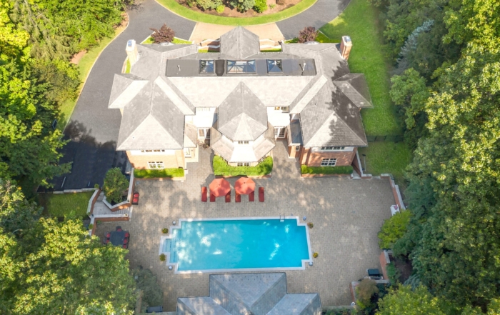 Aerial view of a luxurious residential property in new jersey, featuring a mansion, swimming pool, and lush greenery.