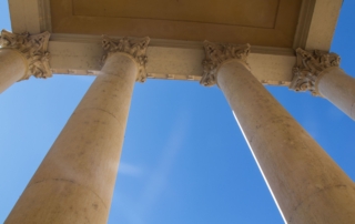 Low angle view of classical stone columns in bright sunlight.