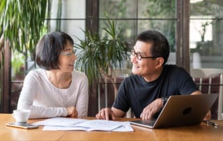 Two people discussing investments at a table, surrounded by tech and paperwork.