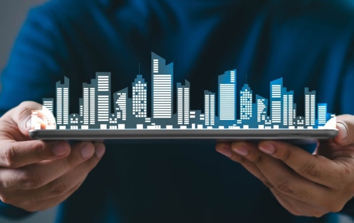 A person holds a tablet displaying a digital cityscape, highlighting technological advancements in real estate.