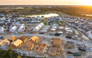 Aerial view of a developing residential construction site with homes and a swimming pool at sunset